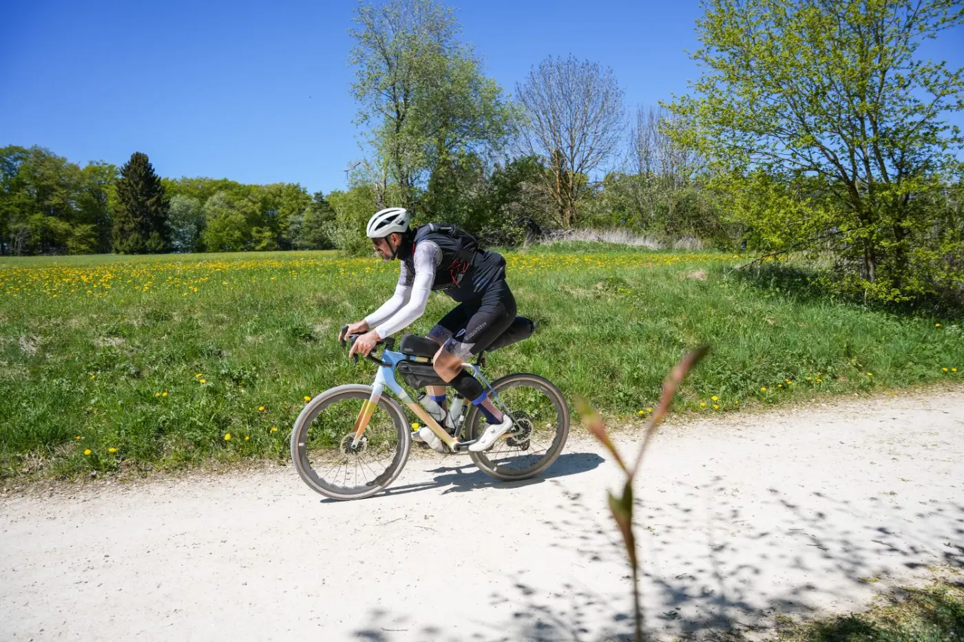 Fahrer auf Schotterweg an blühender Frühlingswiese