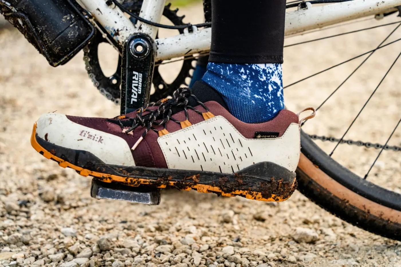 Detail eines schlammigen Gravel-Schuhs am Pedal